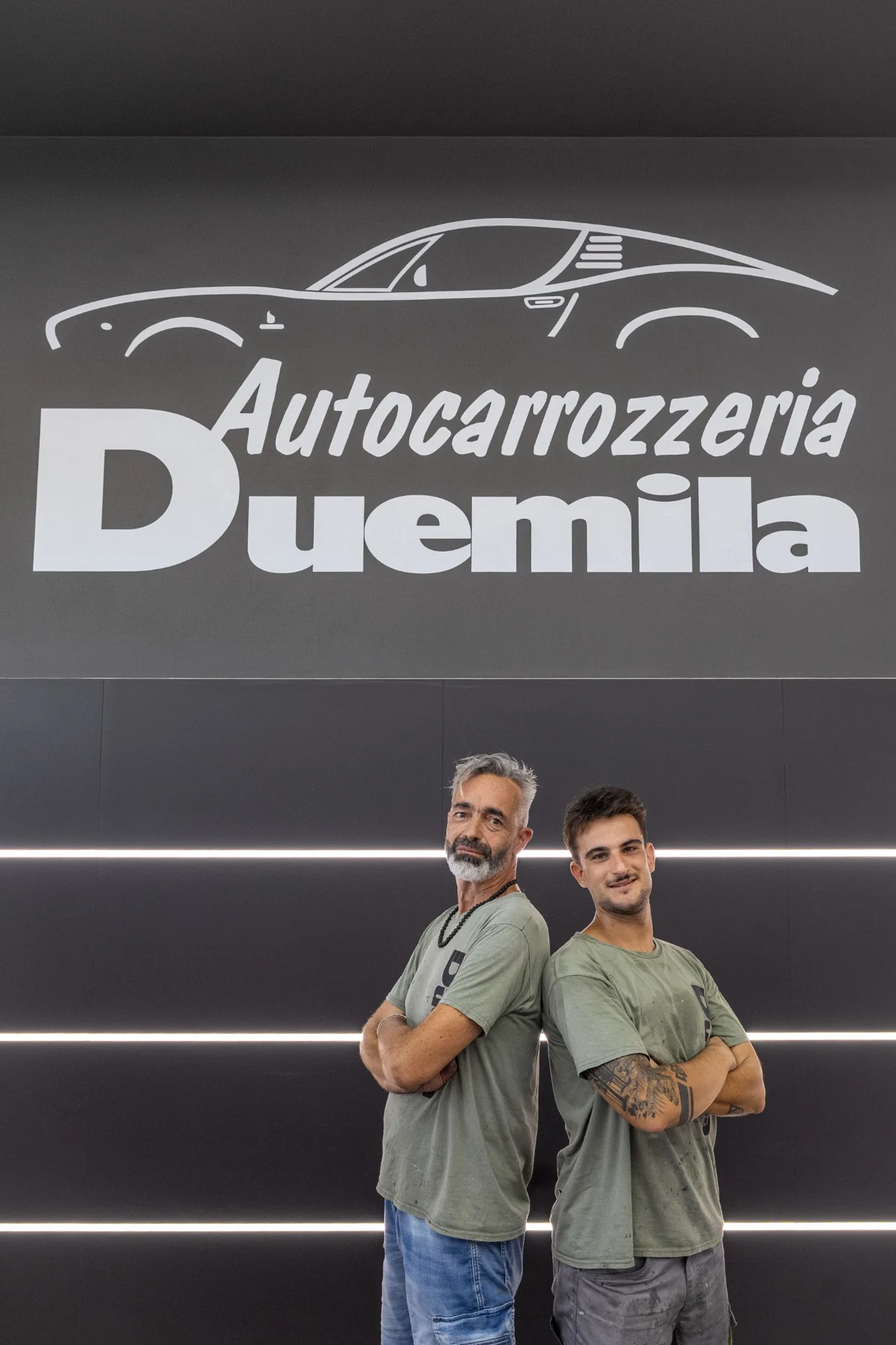 Luca Pinochi e Lorenzo davanti al logo di Autocarrozzeria Duemila